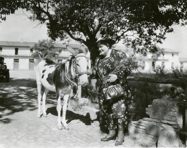 Scena del film "Gatta ci cova" - Righelli, Gennaro, 1937 - Sotto un albero, vicino ad un muretto: Rosina Anselmi e un asino.