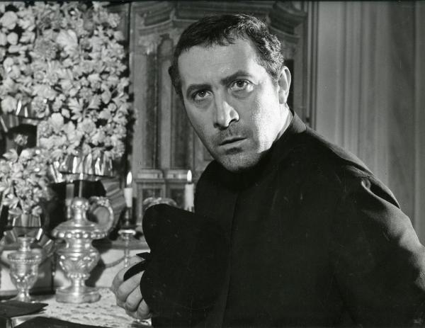 Scena del film "Il gattopardo" - Visconti, Luchino, 1963 - Primo piano di Romolo Valli mentre guarda dritto di fronte a sé tenendo con la mano destra il copricapo talare.