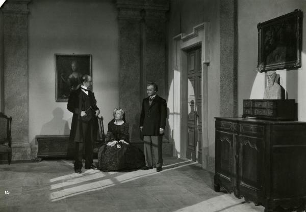 Scena del film "Gelosia" - Poggioli, Ferdinando Maria, 1943 - In un salotto: al centro Wanda Capodaglio seduta che scambia uno sguardo con Francesco Coop a sinistra. A destra, Andrea D'Amaniera guarda Coop.