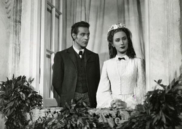 Scena del film "Gelosia" - Poggioli, Ferdinando Maria, 1943 - Affacciati a una finestra: Roldano Lupi, a sinistra, guarda verso Elena Zareschi, a destra, mentre guarda dritto di fronte a sé.