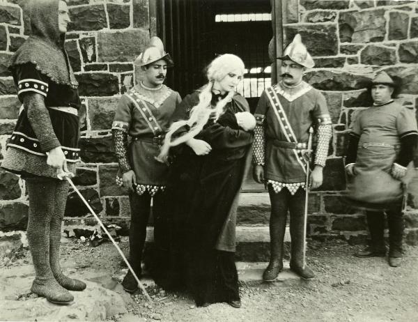 Scena del film "Genoeffa di Brabante" - Zeglio, Primo, 1947 - Di fronte a una porta con due gradini: al centro, Harriet Medin tiene in braccio e guarda il suo bambino. Attorno, attori non identificati in vesti di guardie.