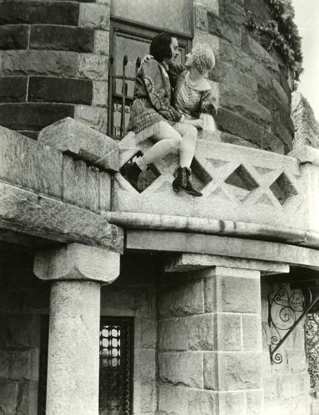 Scena del film "Genoeffa di Brabante" - Zeglio, Primo, 1947 - Gar Moore e Harriet Medin sono appoggiati al cornicione di un balcone. Lei tiene il braccio destro attorno alle spalle di lui. Entrambi si guardano intensamente negli occhi.