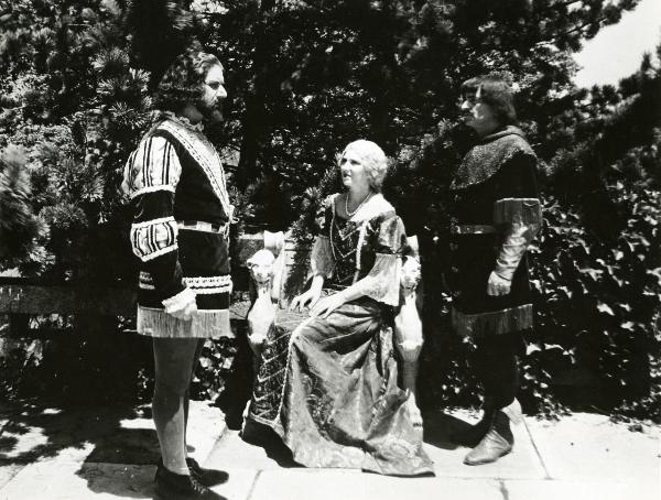 Scena del film "Genoeffa di Brabante" - Zeglio, Primo, 1947 - In un cortile, Harriet Medin è seduta al centro. A destra e a sinistra, in piedi, due attori non identificati.