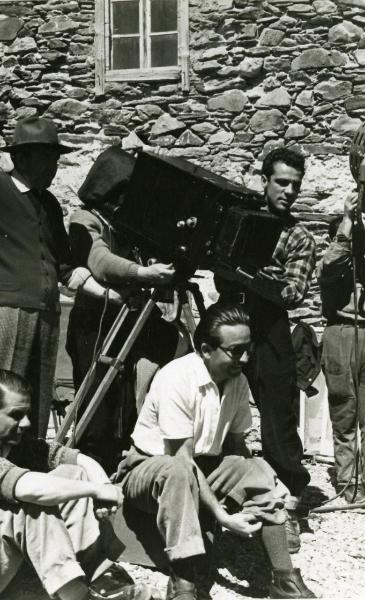 Fotografia sul set "Gente così" - Cerchio, Fernando, 1949 - Mentre si sistema un calzino, il regista Cerchio. Dietro, con un cappello, il direttore della fotografia Arturo Gallea. Insieme a loro, un gruppo di operatori non identificati.