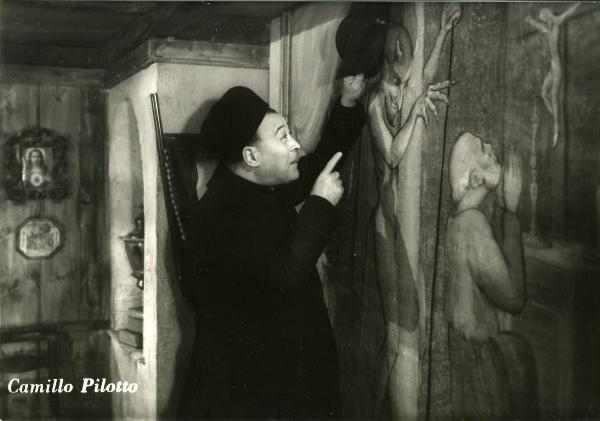 Scena del film "Gente così" - Cerchio, Fernando, 1949 - Mezza figura di Camillo Pilotto nei panni di prete mentre guarda un affresco rappresentante un diavolo.