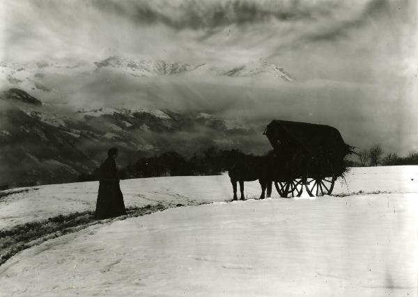 Scena del film "Giacomo l'idealista" - Lattuada, Alberto, 1942 - In un paesaggio montano innevato: un'attrice non identificata cammina verso una carrozza con dei cavalli trainata da un altro attore non identificato.