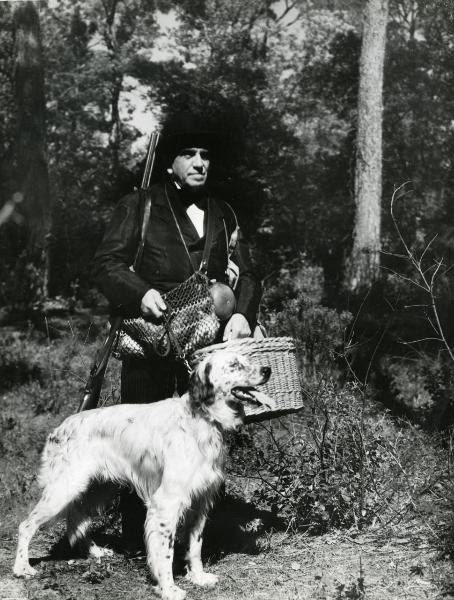 Scena del film "Gioco d'azzardo" - Bassi, Parsifal, 1943 - In mezzo a un bosco: figura intera di Armando Falconi in tenuta da caccia con un cane al guinzaglio.