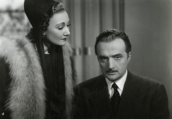 Scena del film "Gioco pericoloso" - Malasomma, Nunzio, 1942 - Elsa Merlini, a sinistra, guarda intensamente Renato Cialente, a destra, che guarda dritto davanti a sé, assorto.