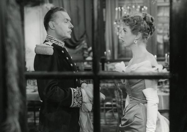 Scena del film "I gioielli di Madame de..." - Ophuls, Max, 1953 - Dietro a un infisso in ferro di una finestra: mezze figure di Charles Boyer, a sinistra, e di Danielle Darrieaux, a destra. I due attori si guardano negli occhi.