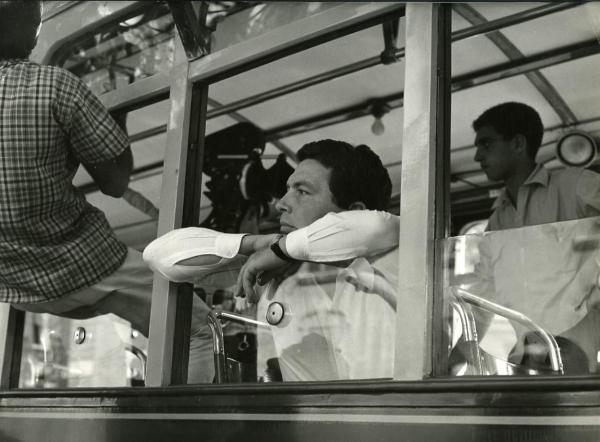 Fotografia di set "I giorni contati" - Petri, Elio, 1962 - Il regista Elio Petri appoggiato al finestrino abbassato di un mezzo di trasporto.
