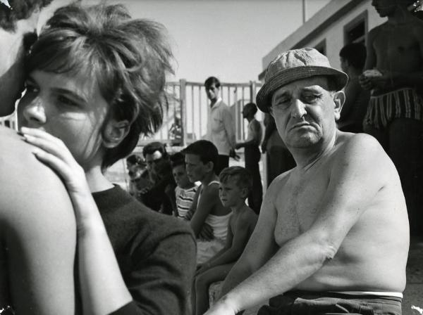 Scena del film "I giorni contati" - Petri, Elio, 1962 - A destra, a petto nudo e con un cappellino, Salvo Randone guarda in basso. In primo piano a sinistra, due attori non identificati si abbracciano. Attorno, attori non identificati.