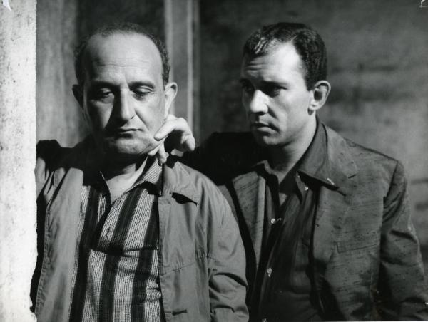 Scena del film "I giorni contati" - Petri, Elio, 1962 - Primi piani di Salvo Randone, a sinistra mentre guarda in basso, e di Paolo Ferrari, a destra mentre pizzica una guancia a Randone.