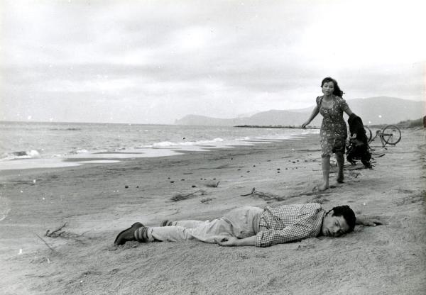 Scena del film "Giorni d'amore" - De Sanctis, Giuseppe, Savona, Leopoldo, 1954 - Sul bagnasciuga: Marcello Mastroianni giace steso sulla sabbia svenuto. Marina Vlady gli sta correndo incontro. In fondo, la bici ribaltata.