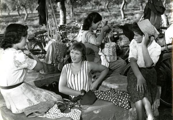 Scena del film "Giorni d'amore" - De Sanctis, Giuseppe, Savona, Leopoldo, 1954 - Marina Vlady, al centro in un pozzo, mentre si lega qualcosa alla vita. Attorno, tre attrici non identificate sedute sul pozzo in pietra.