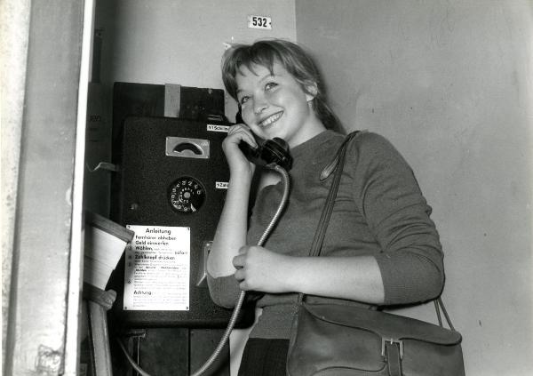 Scena del film "Giorni d'amore" - De Sanctis, Giuseppe, Savona, Leopoldo, 1954 - Marina Vlady a una cabina telefonica. L'attrice, sorridendo, tiene con la mano destra la cornetta del telefono e con la destra il filo.