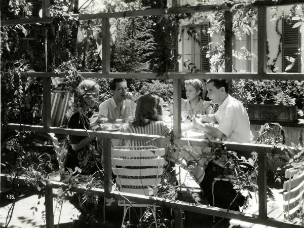 Scena del film "Giorni felici" - Franciolini, Gianni, 1942 - Seduti a un tavolo all'aperto mentre mangiano, da sinistra a destra: Lilia Silvi, Leonardo Cortese, Vera Carmi, Paolo Stoppa e un'attrice non identificata di spalle.