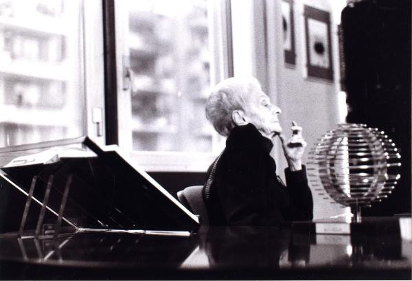 Fotografia sul set di "Un giorno alla Olivetti" - Veronesi, Luigi, 1947 - Al centro, Rita Levi Montalcini seduta su una sedia con aria pensante. In primo piano, un leggio e un globo.