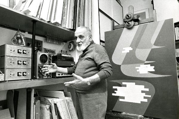 Fotografia sul set di "Un giorno alla Olivetti" - Veronesi, Luigi, 1947 - Mezza figura di Luigi Veronesi mentre mostra delle apparecchiature.