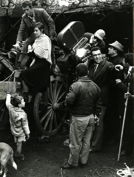 Fotografia sul set di "Un giorno da leoni" - Loy, Nanni, 1961 - A sinistra, su un carro, Valeria Moriconi insieme a un attore non identificato. A destra, alcuni operatori non identificati con la cinepresa tra cui Marcello Gatti.