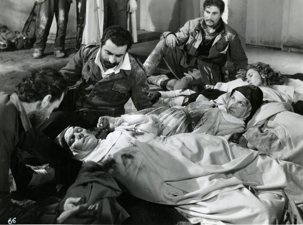Scena del film "Un giorno nella vita" - Blasetti, Alessandro, 1946 - In primo piano, alcune attrici non identificate in veste da suore sono sdraiate a terra morte. Attorno, a sinistra, due attori non identificati e in fondo, Amedeo Nazzari.