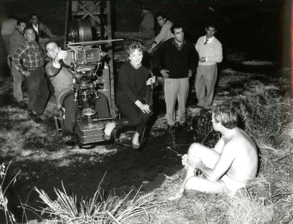 Fotografia sul set di "Giovani mariti" - Bolognini, Mauro, 1957 - Nella postazione di ripresa, il regista Mauro Bolognini. Accanto a lui, l'attrice Rosy Mazzacurati. Attorno, attori e operatori non identificati.