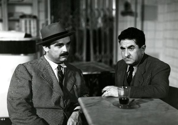 Scena del film "Gioventù perduta" - Germi, Pietro, 1947 - Seduti a un tavolino: a sinistra, un attore non identificato. A destra, Nando Bruno. Entrambi hanno lo sguardo perso nel vuoto.