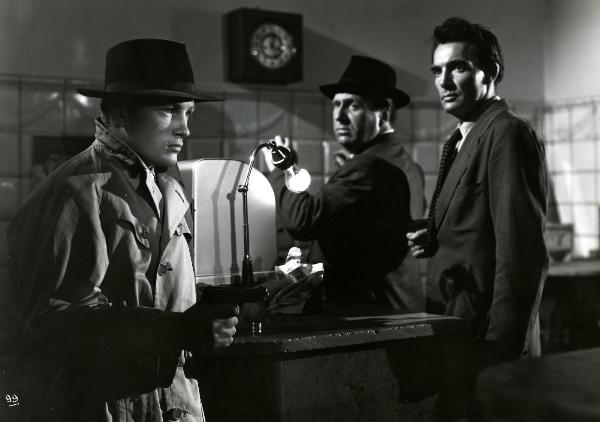 Scena del film "Gioventù perduta" - Germi, Pietro, 1947 - A sinistra, Jacques Sernas tiene nella mano destra una pistola.  A destra, un attore non identificato con una pistola nella mano destra, tiene in ostaggio un altro attore non identificato.