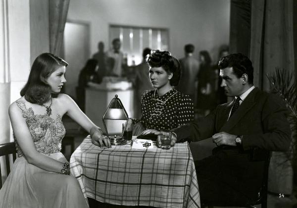 Scena del film "Gioventù perduta" - Germi, Pietro, 1947 - Attorno a un tavolino: Massimo Girotti e Leda Vallini si scambiano uno sguardo. Al centro, Carla Del Poggio guarda Leda Vallini.