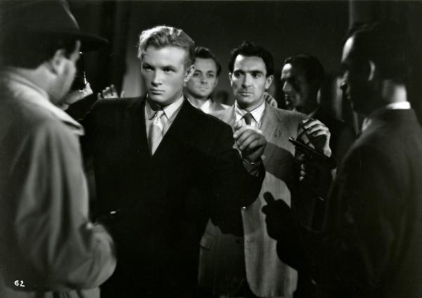 Scena del film "Gioventù perduta" - Germi, Pietro, 1947 - In mezzo ad attori non identificati con le pistole, Jacques Sernas, a sinistra, e Massimo Girotti, a destra, tengono le mani in alto.