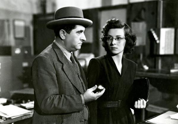Scena del film "Gioventù perduta" - Germi, Pietro, 1947 - Mezza figura di Nando Bruno, a sinistra, e di un'attrice non identificata a destra. L'attore tiene in mano un oggetto non identificato. Nel mentre, i due si scambiano uno sguardo.