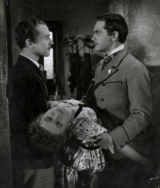 Scena del film "Giù il sipario" - Matarrazzo, Raffaello, 1940 - A sinistra, Andrea Checchi. A destra, Giulio Panicali. I due attori, guardandosi negli occhi, tengono fra le braccia Lilia Silvi svenuta.
