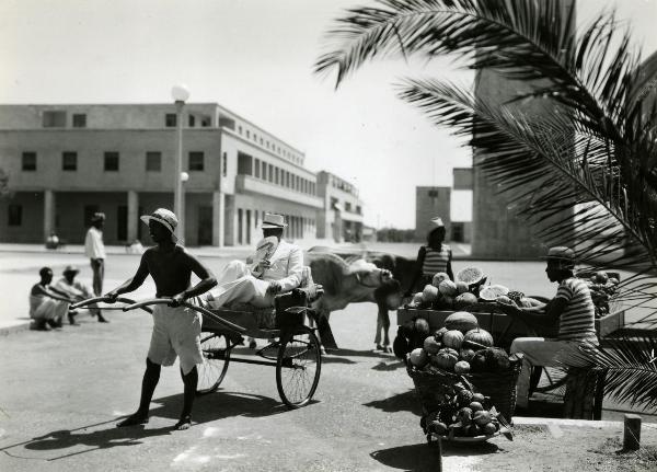 Scena del film "Giungla" - Malasomma, Nunzio, 1942 - In una piazza, alcuni attori non identificati svolgono scene della vita quotidiana: vendere la frutta, tirare un carretto.