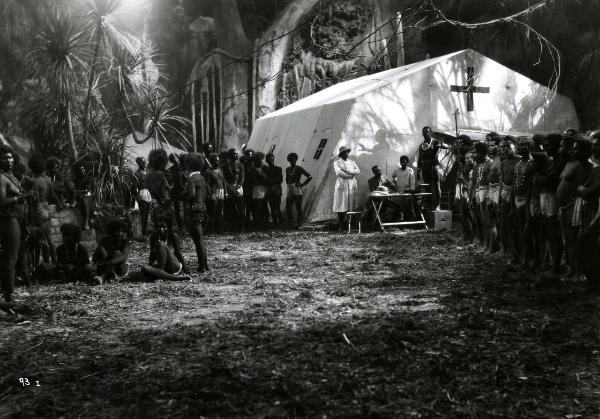 Scena del film "Giungla" - Malasomma, Nunzio, 1942 - In mezzo alla giungla, una tribù di indigeni si raduna attorno a una tenda medica da campo.
