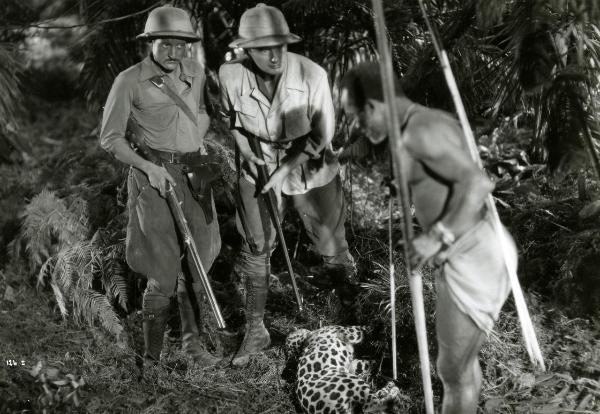 Scena del film "Giungla" - Malasomma, Nunzio, 1942 - Rodolfo Fernau, al centro, insieme a due attori non identificati guardano il corpo di un felino che giace a terra.

