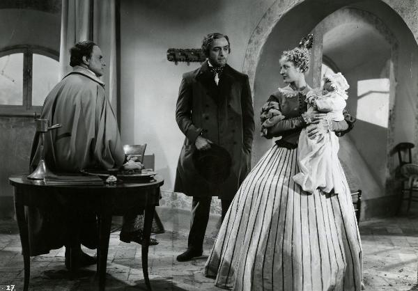 Scena del film "Giuseppe Verdi" - Gallone, Carmine, 1938 - A sinistra, un attore non identificato. Al centro, Fosco Giachetti. Entrambi guardano Germana Paolieri, a destra, mentre tiene in braccio un bambino.










