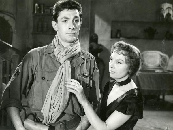 Scena del film "Il grande giuoco" - Siodmak, Robert, 1954 - A sinistra, Jean Claude Pascal in veste da soldato. A destra, Arletty gli sistema la sciarpa e guarda verso sinistra.