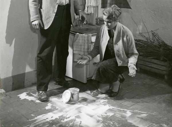 Scena del film "Il grido" - Antonioni, Michelangelo, 1957 - Vicino a un fornello da cucina, Alida Valli in ginocchio con le braccia larghe mentre guarda un pentolino caduto a terra. Di fianco a lei, un attore non identificato.
