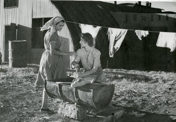 Scena del film "Il grido della terra" - Coletti, Duilio, 1948 - Al centro, Elena Zareschi sta lavando i panni in un lavatoio. A sinistra, Marina Berti le tocca il braccio destro.
