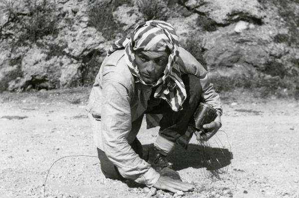 Scena del film "Il grido della terra" - Coletti, Duilio, 1948 - Inginocchiato a terra Renato Bossi sistema un cavo di ferro.
