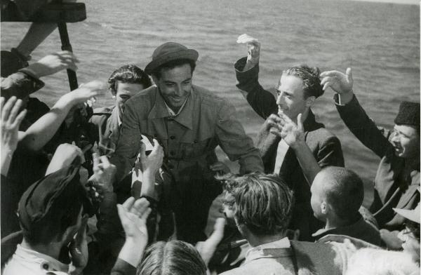 Scena del film "Il grido della terra" - Coletti, Duilio, 1948 - Al centro, Edmondo Costa, viene accolto da molti attori non identificati che gli tendono le mani.
