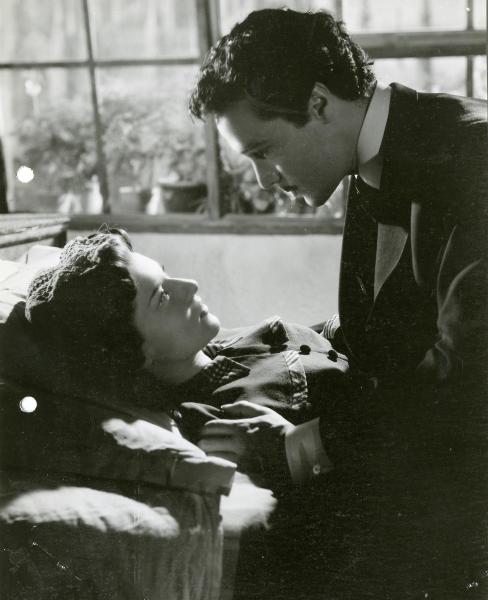 Scena del film "Guarany" - Freda, Riccardo, 1948 - Sdraiata su un letto, Mariella Lotti. Seduto accanto a lei, Antonio Vilar. I due si guardano intensamente.

