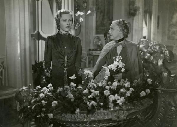 Scena del film "Hanno rapito un uomo" - Righelli, Gennaro, 1938 - Di fronte a una fioriera: a sinistra, Caterina Boratto mentre guarda di fronte a sé mentre a destra, Evelina Paoli mentre guarda la Boratto.