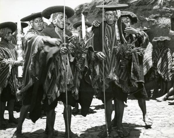 Scena del film "L'impero del sole" - Craveri, Mario, Gras, Enrico, Moser, 1956 - Alcuni attori non identificati in vesti locali danno luogo a una cerimonia. I due attori in primo piano tengono nelle mani una canna di bambù e un mazzo di piante.

