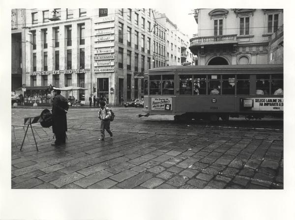 Milano - Piazza Cavour - Fermata Turati della linea metropolitana M3 [nei pressi di] - Tram - Vigile urbano - Bambino che attraversa la strada - Palazzo dell'Informazione sullo sfondo