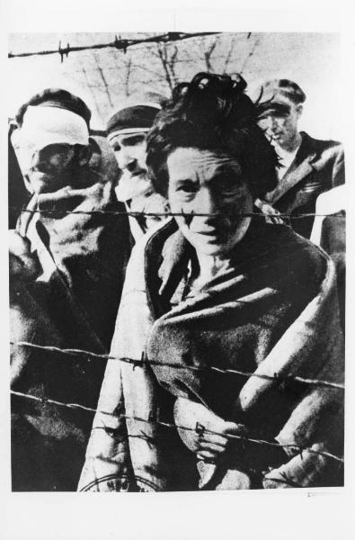 Seconda guerra mondiale - Polonia - Campo di concentramento di Auschwitz - Nazismo - Dopo la liberazione - Ritratto di gruppo: donna e uomini sopravvissuti dietro a reticolato con filo spinato