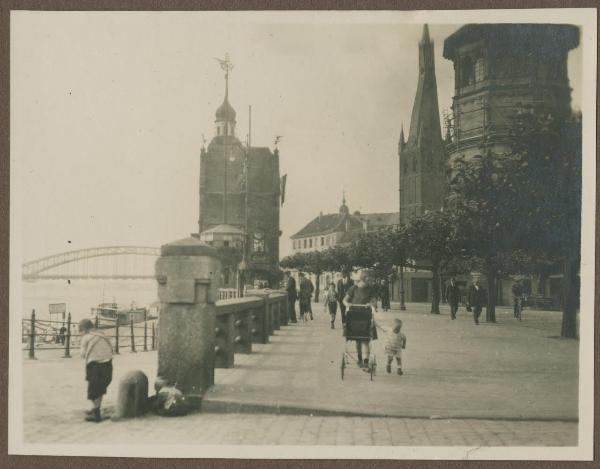 Germania - Dusseldorf (Düsseldorf) - Burgplatz (Piazza del Castello) - Pedoni, bambini - Torre del castello - Campanile della Chiesa di San Lamberto (St. Lambertus) - Fiume Reno - Ponte