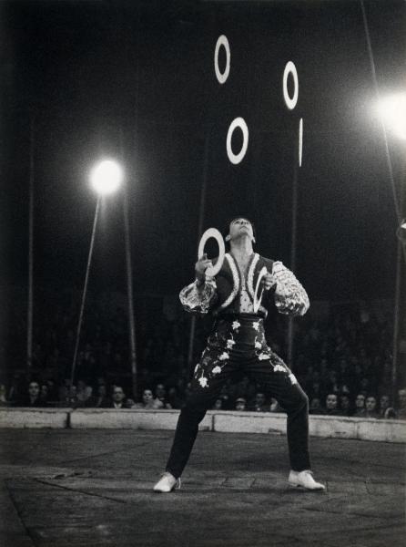 Milano - Circo Orfei - Spettacolo - Artista circense: giocoliere con cerchi - Pubblico sullo sfondo