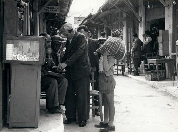 Grecia - Creta - Candia (Iraklio o Herakleio) - Via del Mercato, strada - Esterno - Banco con i libri sacri, lettura - Uomini, bambino con sacco di merce sulla spalla