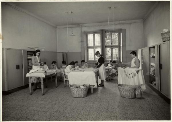 Milano - Via Monterosa - Asilo Mariuccia - Aula di lavoro - Ragazze stirano e rammendano - Armadi - Tavoli - Lampadari - Cesti