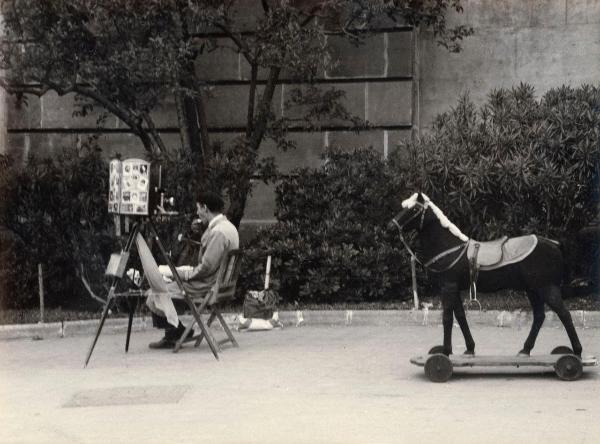 Spagna - Barcellona - Esterno - Strada - Fotografo ambulante seduto, macchina fotografica con cavalletto - Cavallo a dondolo con ruote